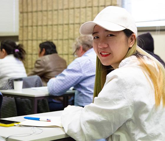 Young woman wearing a hat sitting at a desk 