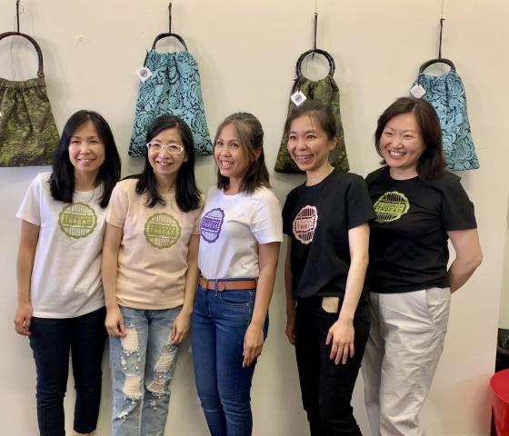 Five students standing in front of fabric bags hanging on a wall