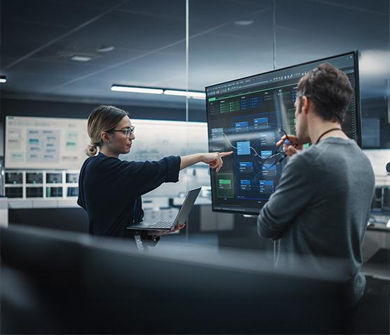 Man and woman in office working using a large display. Image supplied by iStock; gorodenkoff