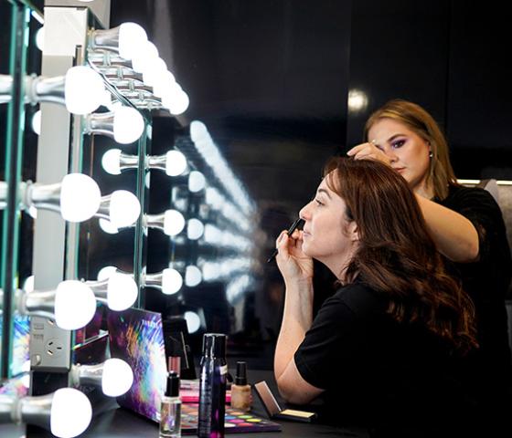 Two NMT lecturers applying makeup in studio including showing reflection in mirror