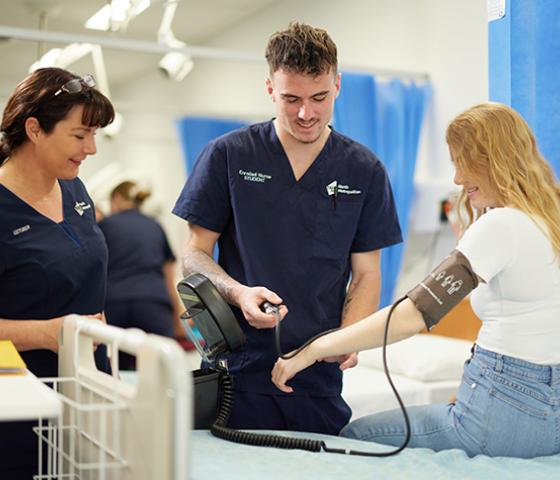 2 students taking a girl's blood pressure