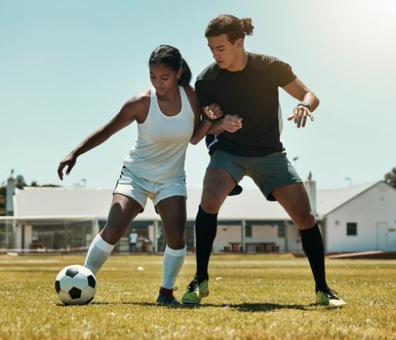 One male and one female soccer player in one on one contest