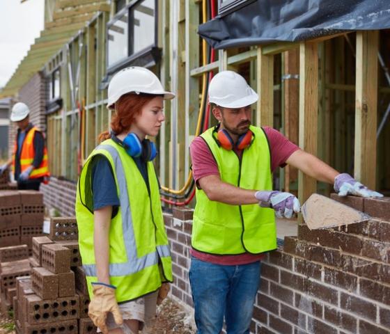 Male showing female how to lay bricks